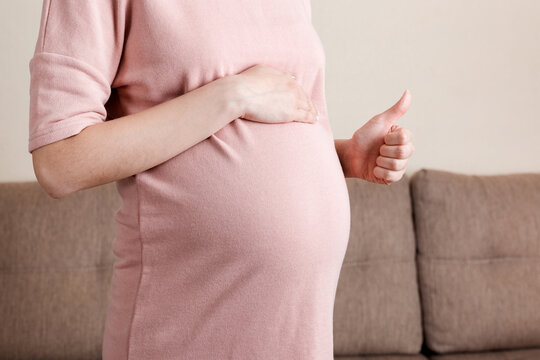 Pregnant woman showing thumbs up at the home