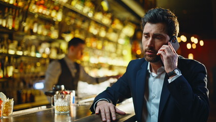 Disappointed man talking smartphone night bar closeup. Guy calling mobile phone