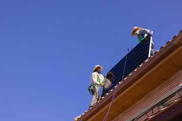 Workers installing solar panels on a house roof