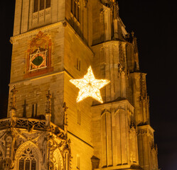 An illuminated star hanging in front of the illuminated tower walls of the "M&uuml;nster unserer lieben Frau" at night. Constance, Baden-W&uuml;rttemberg, Germany.
