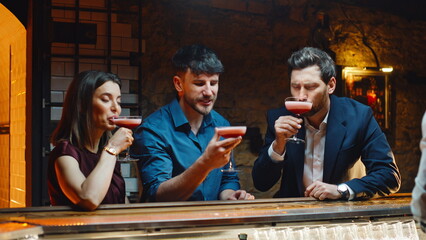 Bar clients drinking cocktails relaxing together on night club party closeup