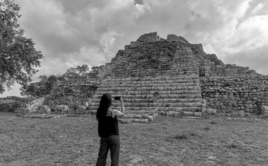 woman standing in front of ancient mayan pyramid ruins in the maya city of oxkintok in yucatan...