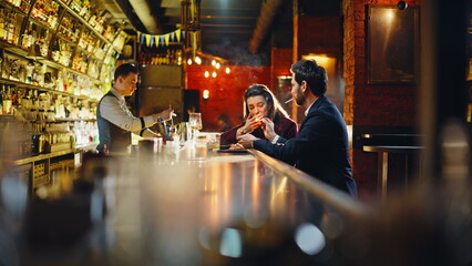 Man offering cigarette flame from matches stylish lady. Elegant couple smoking