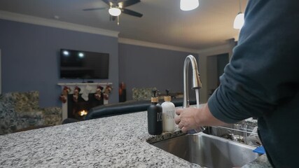 close-up of man washing breakfast bowl and spoon in kitchen sink