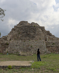 woman standing in front of ancient mayan pyramid ruins in the maya city of oxkintok in yucatan...
