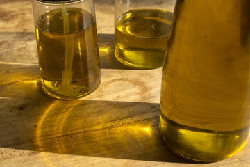 olive oil bottles with golden reflections on wooden table close up