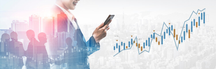 A business professional uses a smartphone to analyze financial data while standing before a skyline, illustrating market trends and technology impact on growth. Gantry