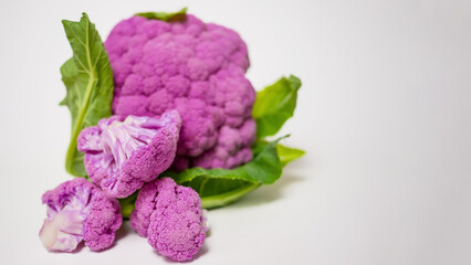 Cut Purple Cauliflower Florets with Leaves on White Background