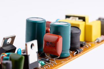 A close-up view of an electronic circuit includes capacitors, resistors, diodes, etc.