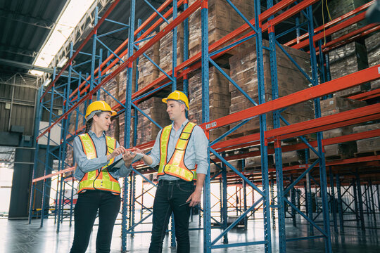 Caucasian man, woman warehouse supervisor wear safety discuss,talk and use clipboard check box package on shelf, product distribution inventory management,Logistics shipping business planning industry - Powered by Adobe