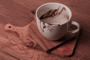 Cup sitting on a wooden surface with traces of coffee remains after a warm drink enjoyed at home