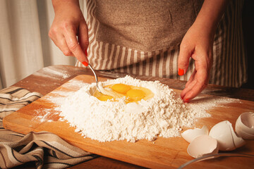 Mixing eggs into flour to make dough for homemade pasta in a cozy kitchen setting