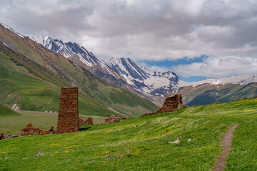 Ancient stone ruins above meadow with dramatic snowy Caucasus backdrop