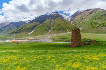 Medieval watchtower above bright meadow in wide Truso mountain valley