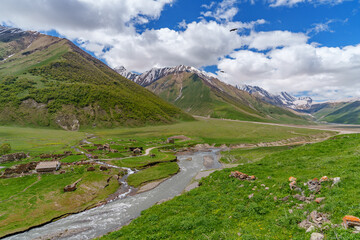 Mountain river and ruined village under bright Caucasus spring sky