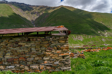 Old stone barn wall with rusted roof in green valley