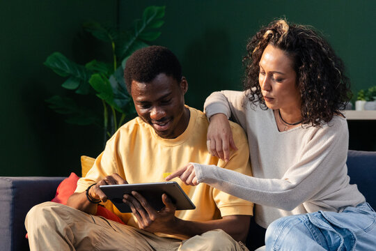 Diverse couple using tablet together at home
