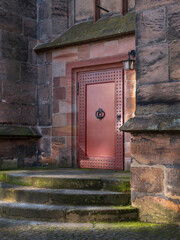 Alte schwere Tür, Seiteneingang zur alten Kirche mit Moos auf Treppen bei Licht