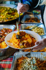 Serving dishes of rice at a vibrant gathering, adults and children enjoying flavorful meals with blurred background for copy space