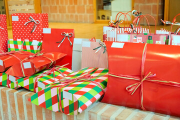 Christmas gifts wrapped in decorative paper arranged on a brick surface with blurred background