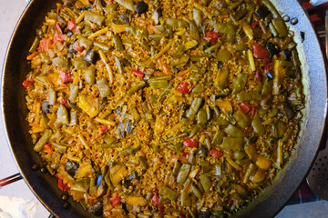 A vibrant Valencian paella with veggies, showcasing communal dining and tradition.