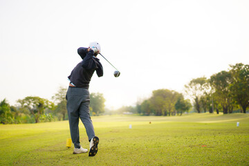 Golfer playing a strong tee off swing on a bright morning fairway. © DG PhotoStock
