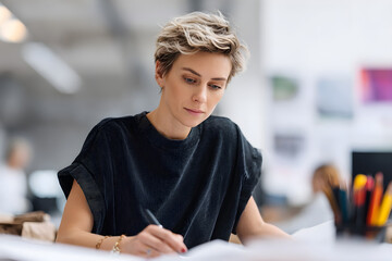 Young non-binary person working attentively in a modern office