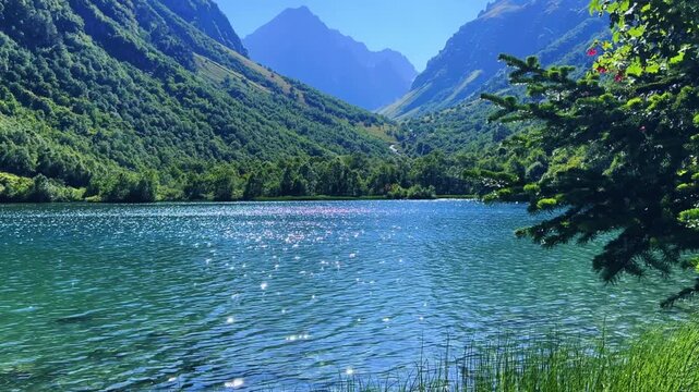 Turquoise water of the Baduk mountain lakes in a mountain valley in the mountains of the North Caucasus, on a sunny summer day. The blue sky and mountain peaks are reflected in the lake. 4К