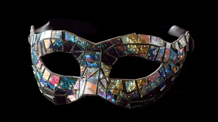 A dazzling masquerade mask, crafted from shimmering iridescent mirror shards, reflecting vibrant colors against a dark background, creating a festive mosaic.