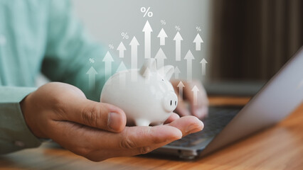 Closeup of hand holding white piggy bank with floating growth icons, representing saving, investment, and financial planning.