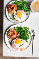 Healthy breakfast. Bagels with fried egg, ham and greens