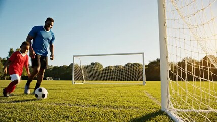 Young person practicing soccer kick near goal during daylight - Powered by Adobe