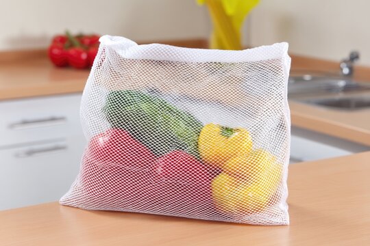 Eco-friendly mesh bag with fresh vegetables on kitchen counter - Powered by Adobe