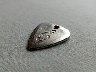 Metallic guitar pick with treble clef engraving