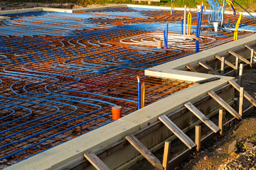 Underfloor heating pipes arranged on reinforced concrete base during modern house foundation work