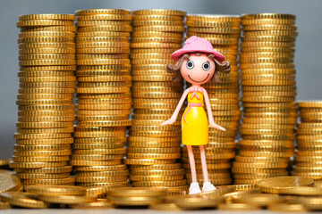 Cute toy girl figurine standing among stacks of shiny gold coins symbolizing savings and wealth