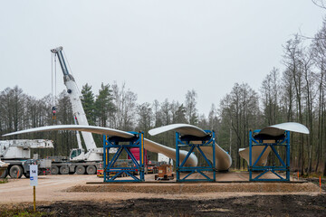 Wind turbine blades prepared for installation with crane and support frames at a renewable energy site