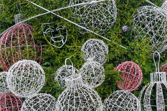Giant decorative Christmas ornaments and wire sculptures displayed on a festive outdoor tree