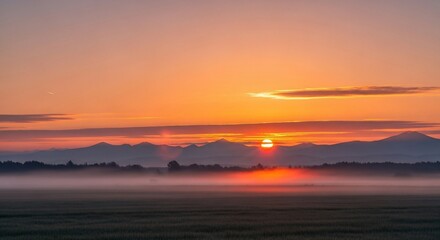 Obraz premium Serene Sunrise Over Misty Landscape with Mountain Silhouette.