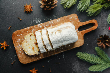 Sweet bread dusted with sugar on a wooden board with pine cones and pine needles