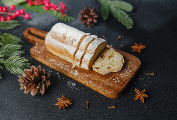Sweet bread dusted with powdered sugar on wood board with pine cones and fir branches