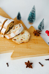 Slices of sweet bread topped with powdered sugar on a wooden board with mini trees and spices