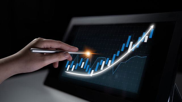 A close-up view of a hand using a stylus on a digital tablet, showcasing a rising financial chart with blue bars and a glowing trend line against a dark background. Impute - Powered by Adobe