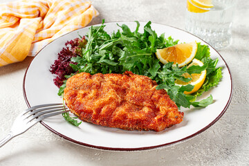 Milanese chicken, Crispy breaded chicken served, with fresh herbs, and lemon wedges,