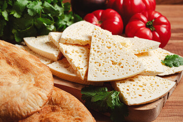 Georgian sliced cheese,on a wooden chopping board, with tomatoes with herbs and lavash, rustic style, Georgian cuisine, no people