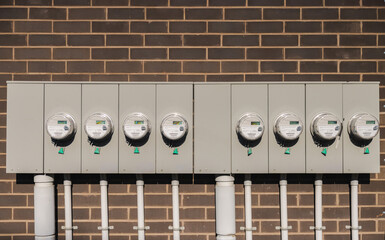 Fototapeta premium Row of modern electric utility meters on brick wall for residential energy measurement