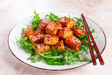 fried salmon slices, teriyaki with sesame seeds, with arugula salad, top view,
