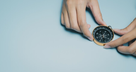Person holding compass on blue background, navigation tool in hand, travel concept with clear space for text or design