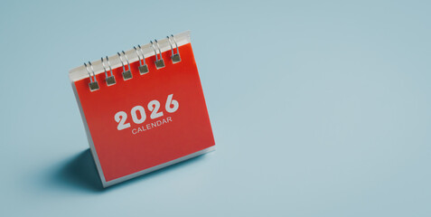 2026 calendar on red cover with spiral binding on blue background, minimal desk accessory for planning and organization