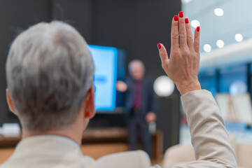 Participant raising hand asking a question during seminar
